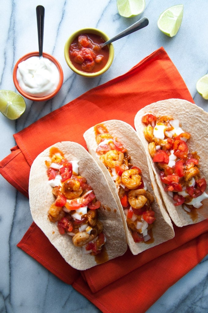 three sweet and smoky BBQ shrimp tacos beside salsa and sour cream