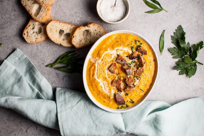 pumpkin and cauliflower soup with ginger in a bowl next to bread slices
