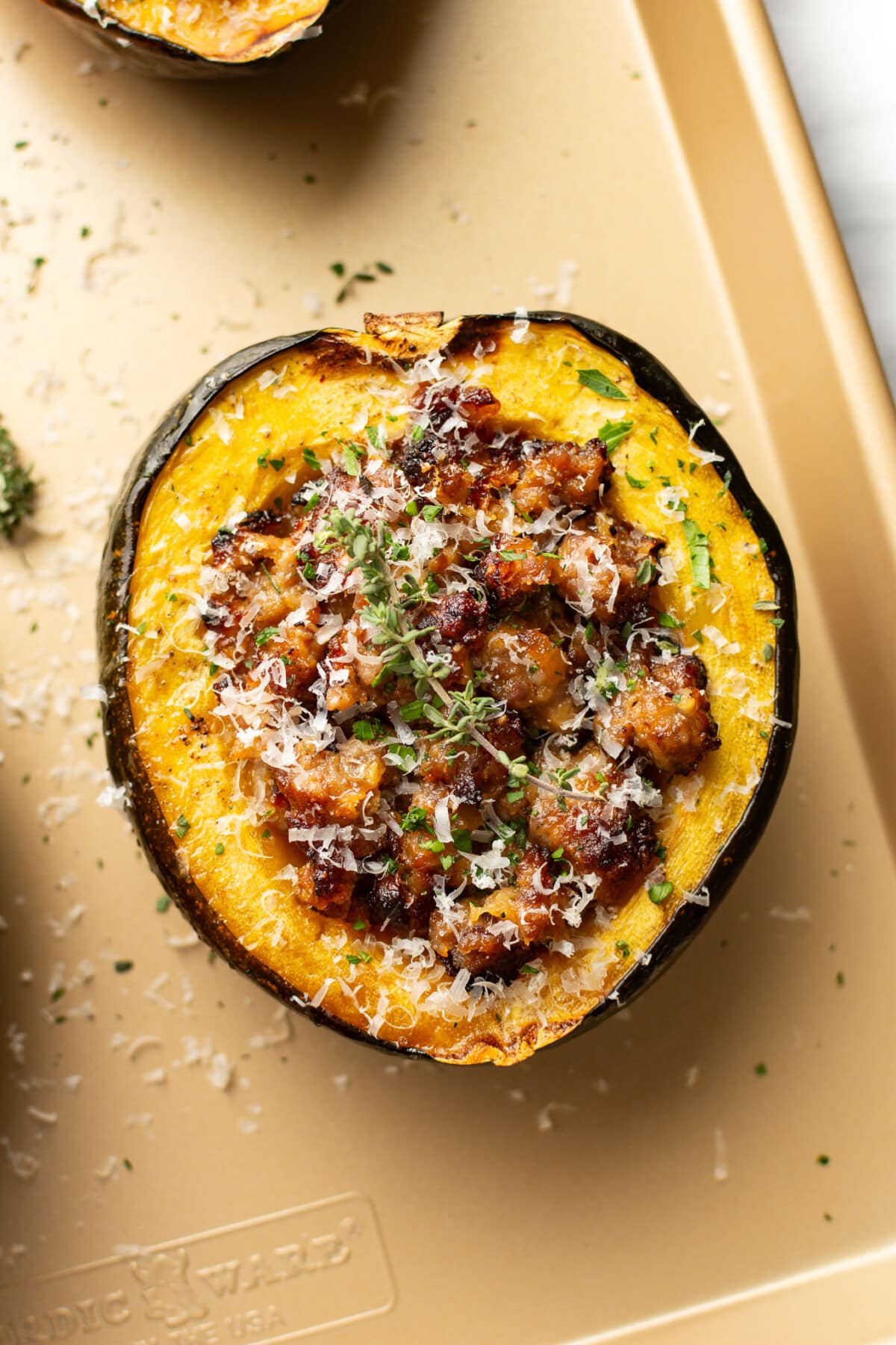 a baking tray with sausage stuffed acorn squash