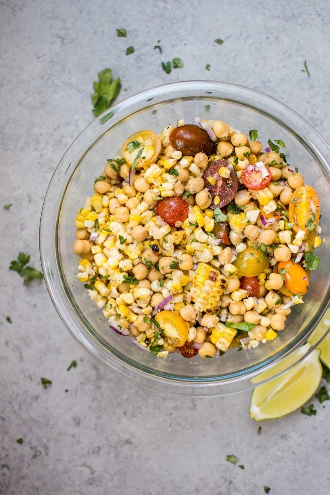 grilled corn and chickpea salad in a glass bowl with lime wedges