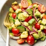 a bowl of cucumber tomato avocado salad with a fork
