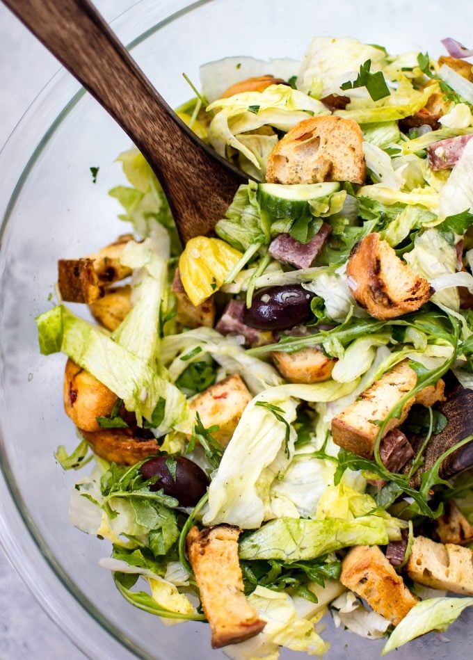 glass bowl with Italian salad and wooden salad utensils