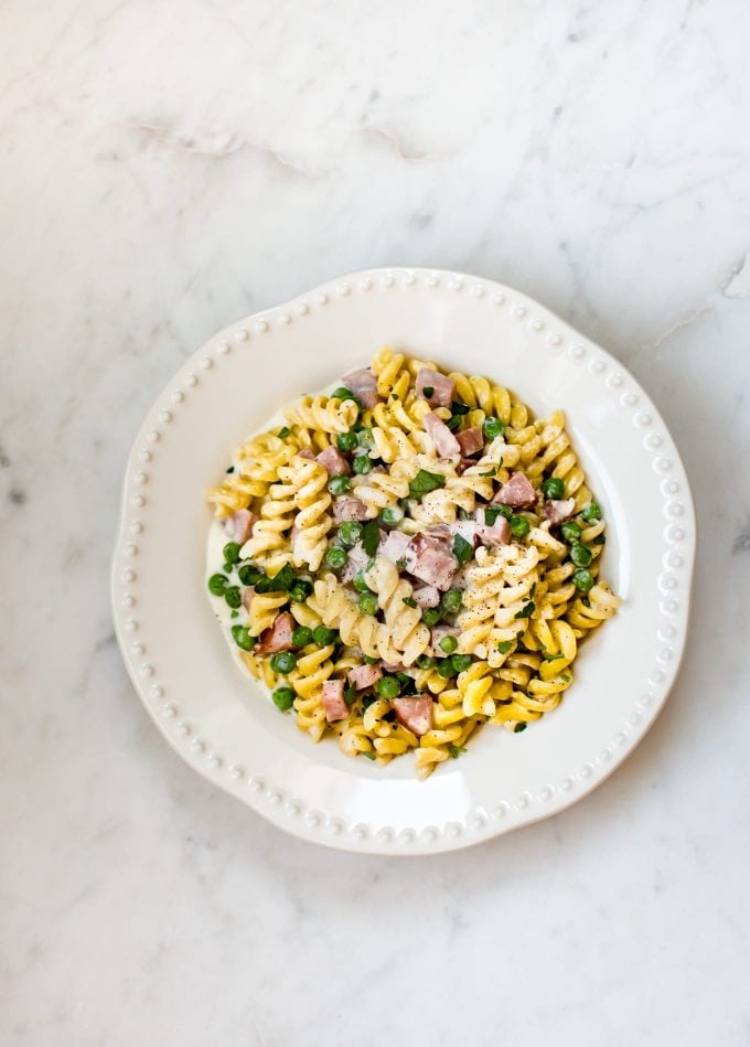 bowl of one-pot ham and pea pasta on a marble surface