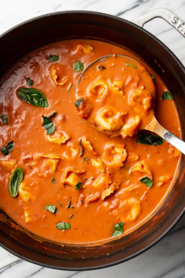 a ladle in a pot of tomato tortellini soup