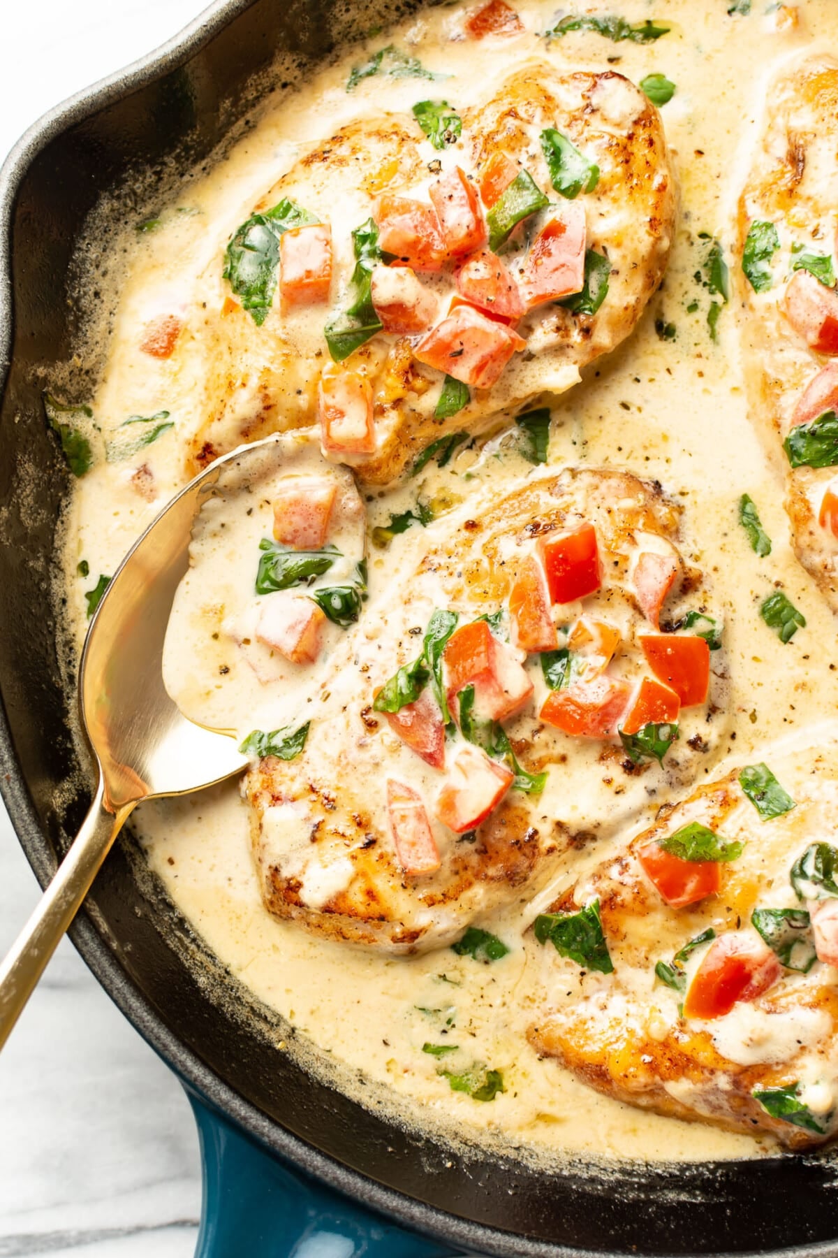 a skillet with creamy tomato basil chicken and a serving spoon