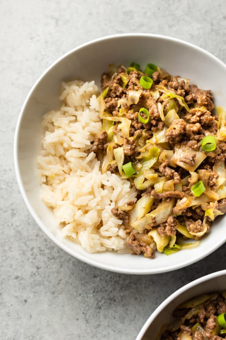 ground beef and cabbage stir fry with rice in two white bowls
