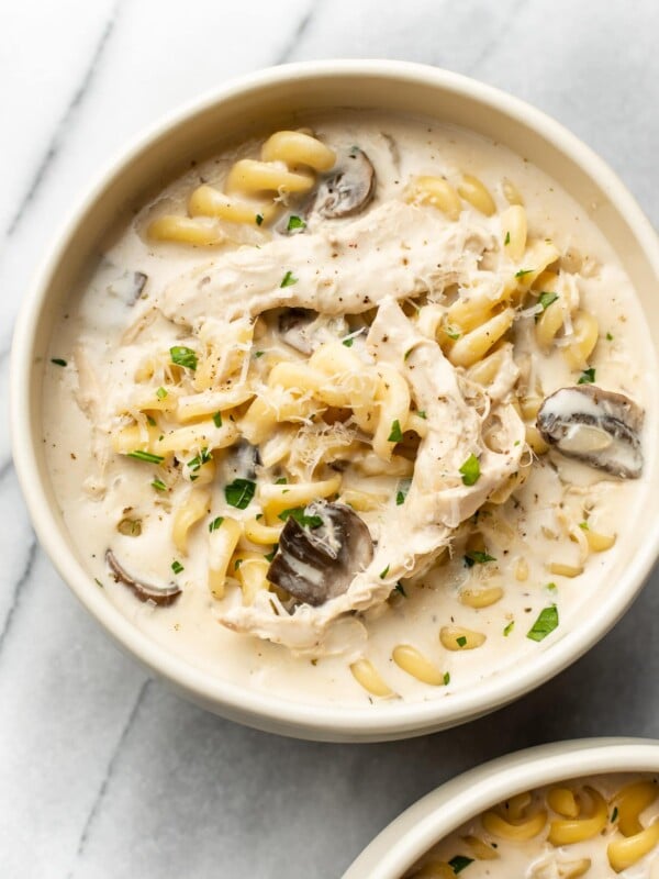 Chicken Tetrazzini Soup in two beige bowls on a marble background