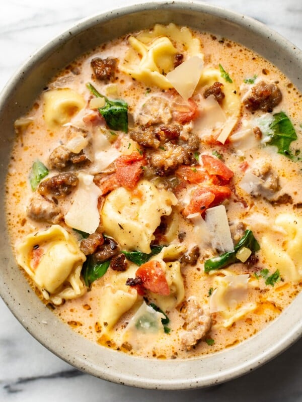 close-up of a bowl of italian sausage tortellini soup with shaved parmesan cheese on top