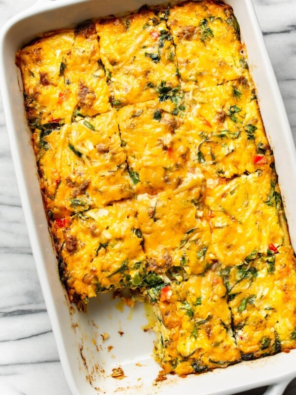 a casserole dish with sausage breakfast casserole with a piece removed