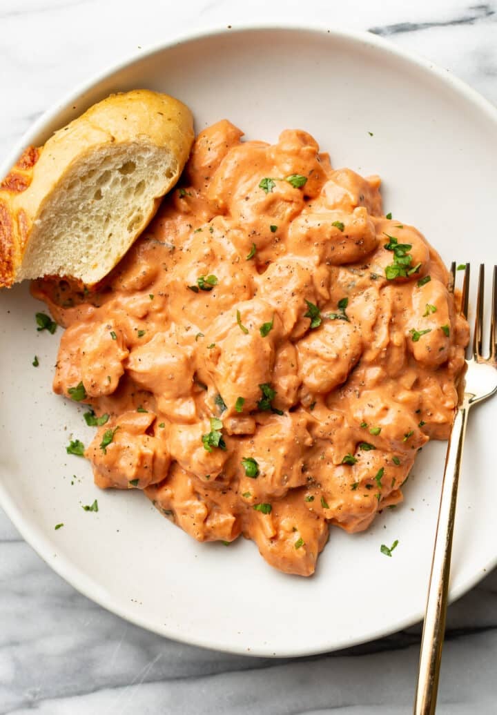 a bowl of gnocchi with a fork and slice of bread