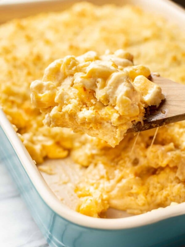 a baking dish with baked mac and cheese and a serving spoon