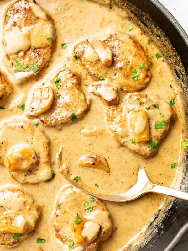 a skillet with creamy garlic pork tenderloin and a serving spoon