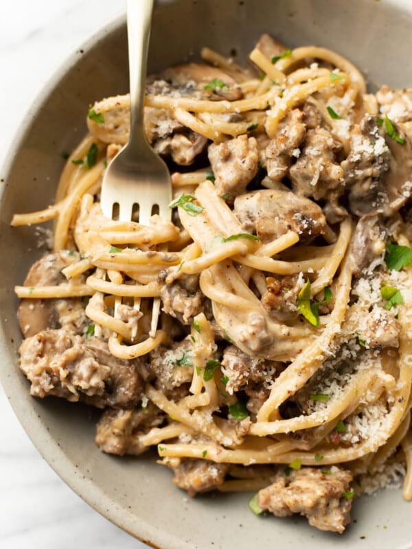 a bowl of italian sausage and mushroom pasta with a fork