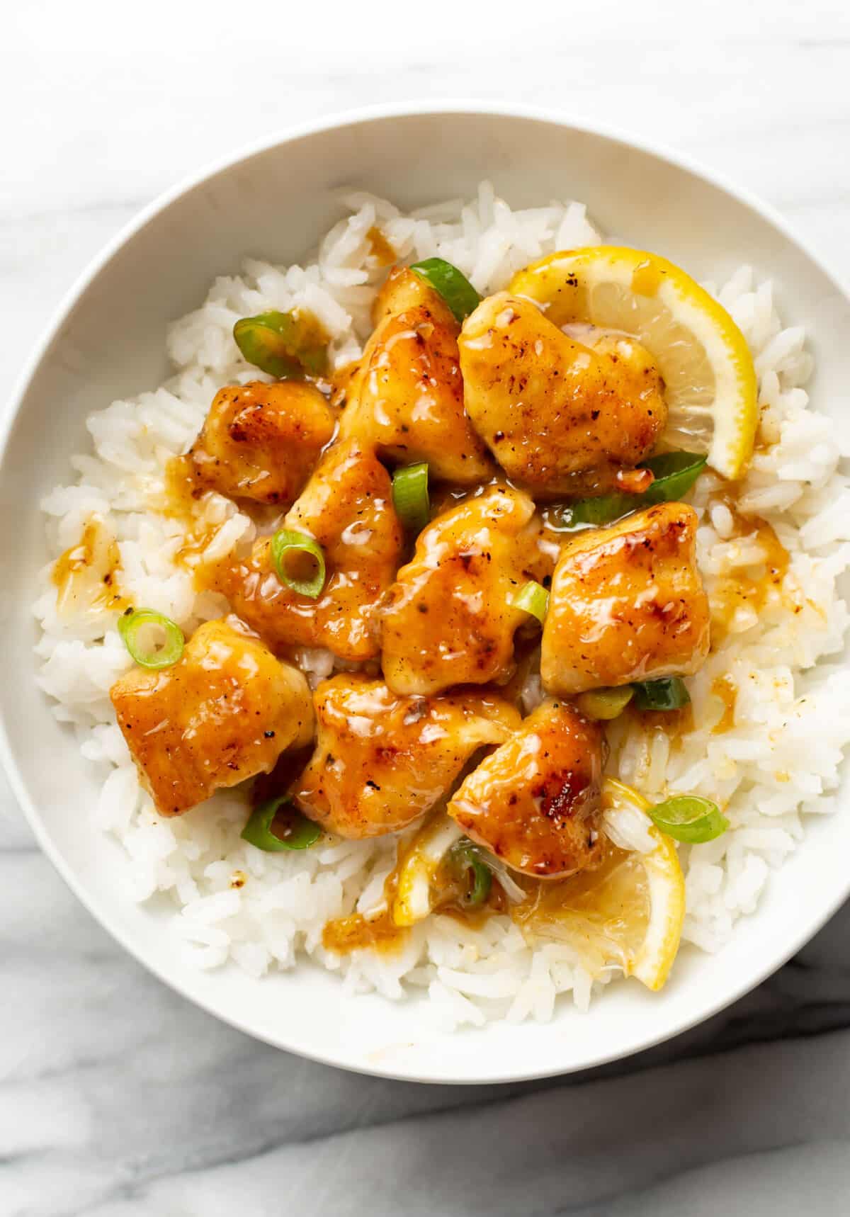 a bowl of chinese lemon chicken over rice