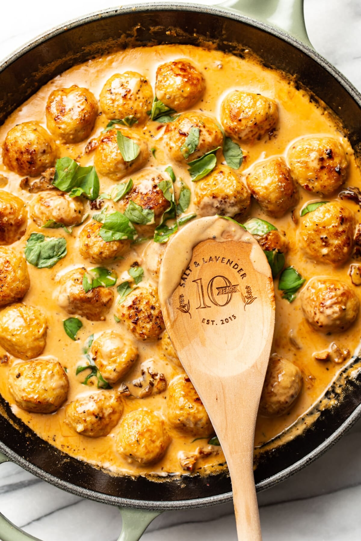 a skillet with marry me meatballs and a wooden spoon
