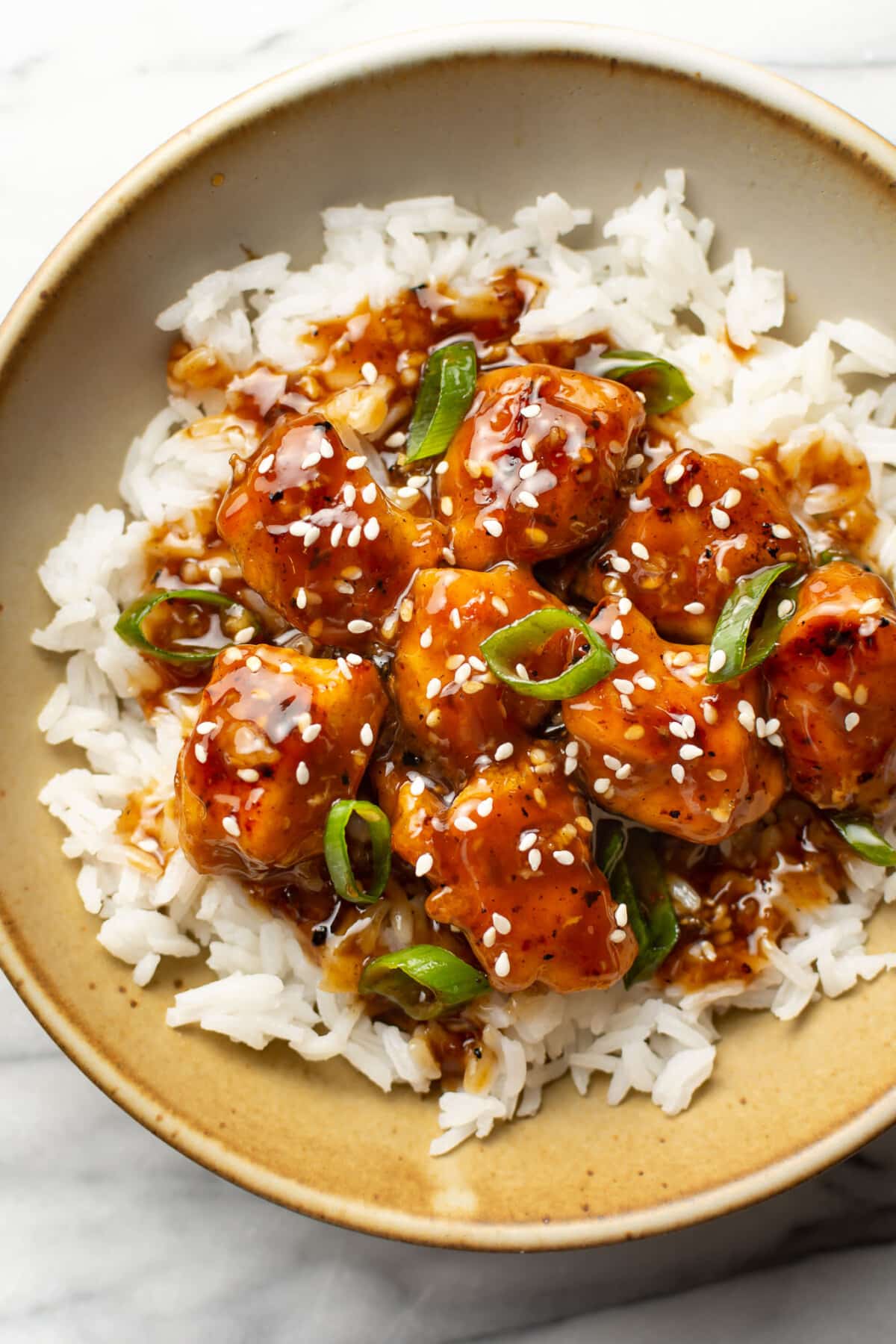 a bowl of sesame chicken with rice