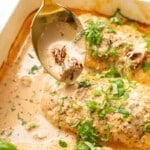 a baking dish with baked marry me chicken breasts and a serving spoon