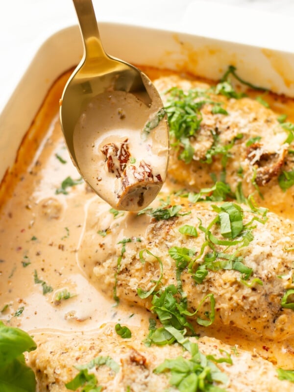 a baking dish with baked marry me chicken breasts and a serving spoon