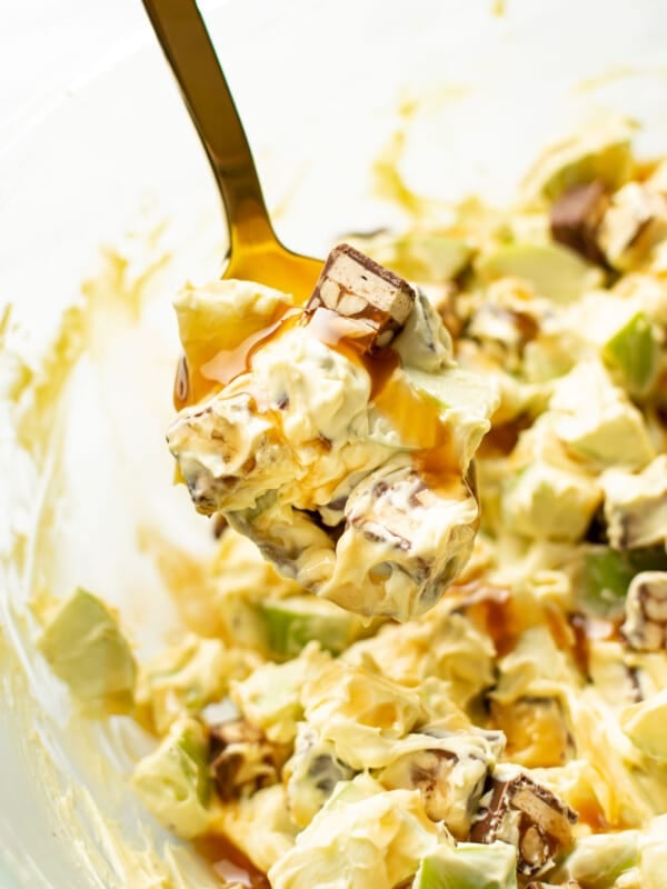 a bowl of snickers apple salad with a serving spoon