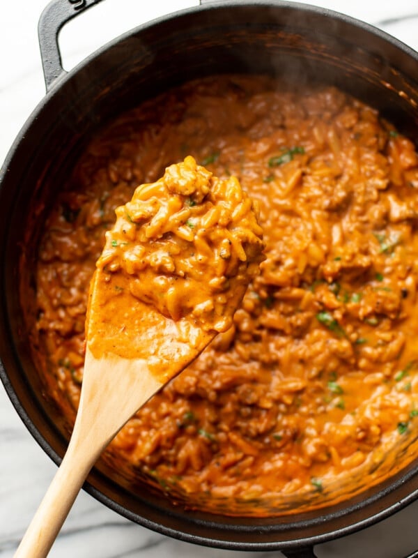 a pot of spicy italian sausage orzo with a wooden spoon