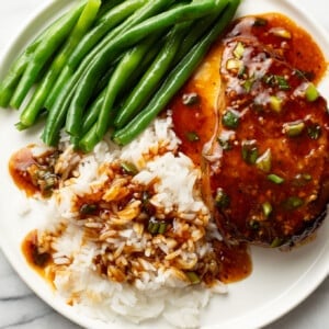 a plate with honey garlic pork chops, green beans, and rice