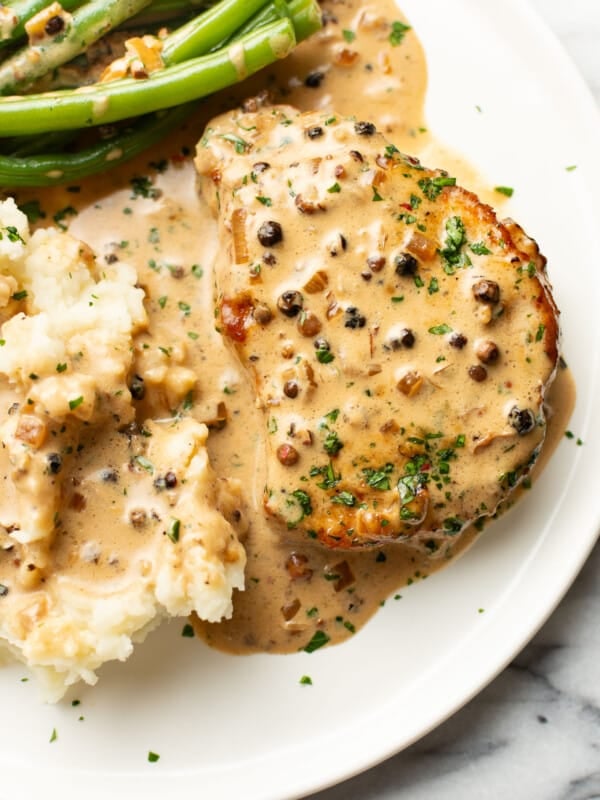 a plate with peppercorn pork chops, green beans, and mashed potatoes