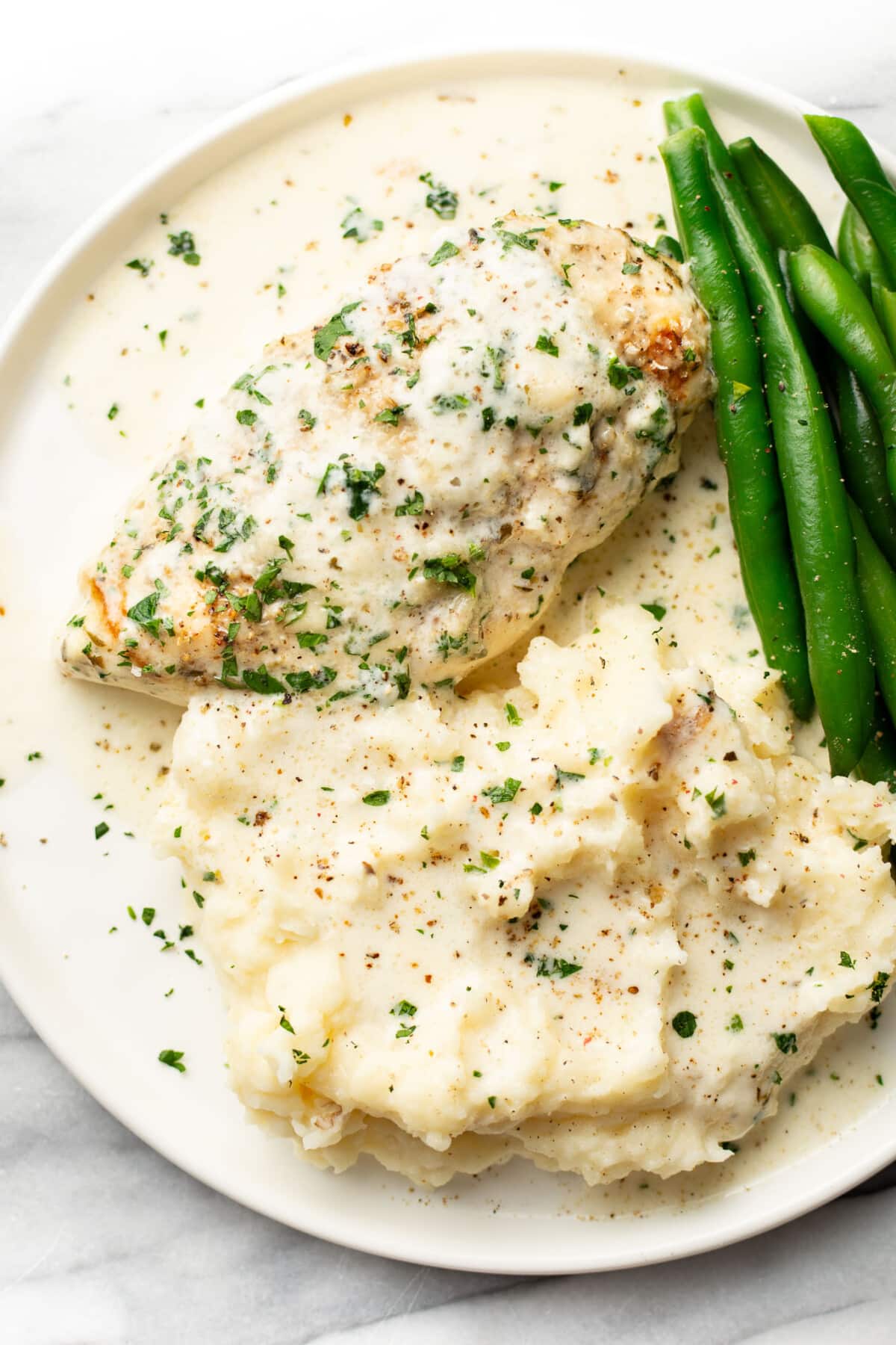 a plate with creamy baked white wine chicken, green beans, and mashed potatoes