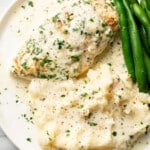 a plate with creamy baked white wine chicken, green beans, and mashed potatoes