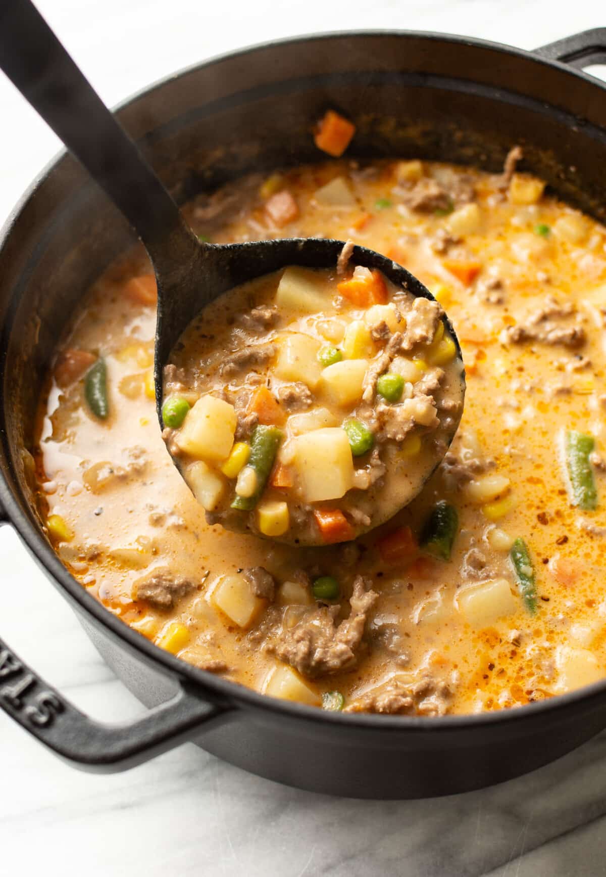a dutch oven with shepherd's pie soup and a ladle