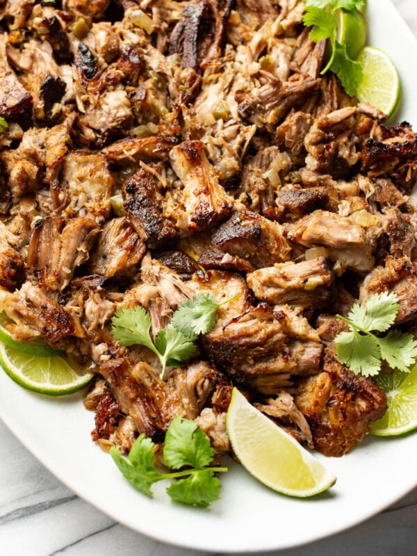 a plate with carnitas and lime wedges