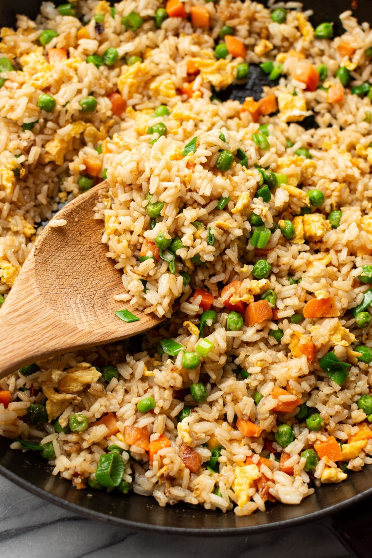 a skillet with fried rice and a wooden spoon
