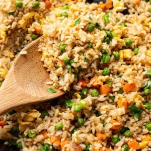 a skillet with fried rice and a wooden spoon