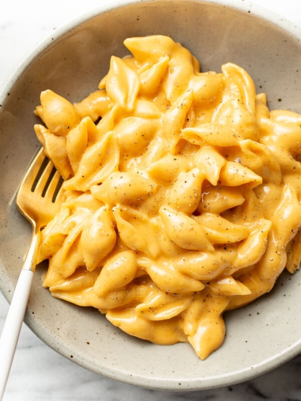 a bowl of cheesy velveeta and shells with a fork