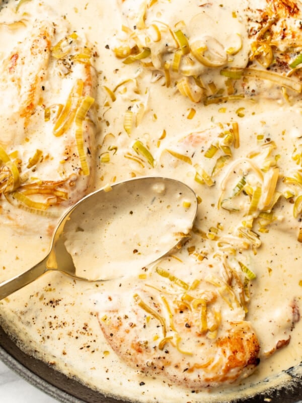 a skillet with creamy leek chicken and a serving spoon