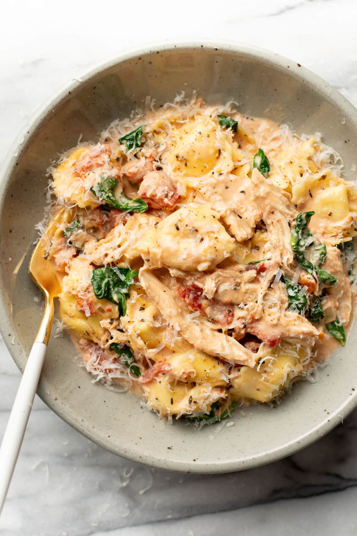 a bowl of one pan tortellini with chicken and a fork