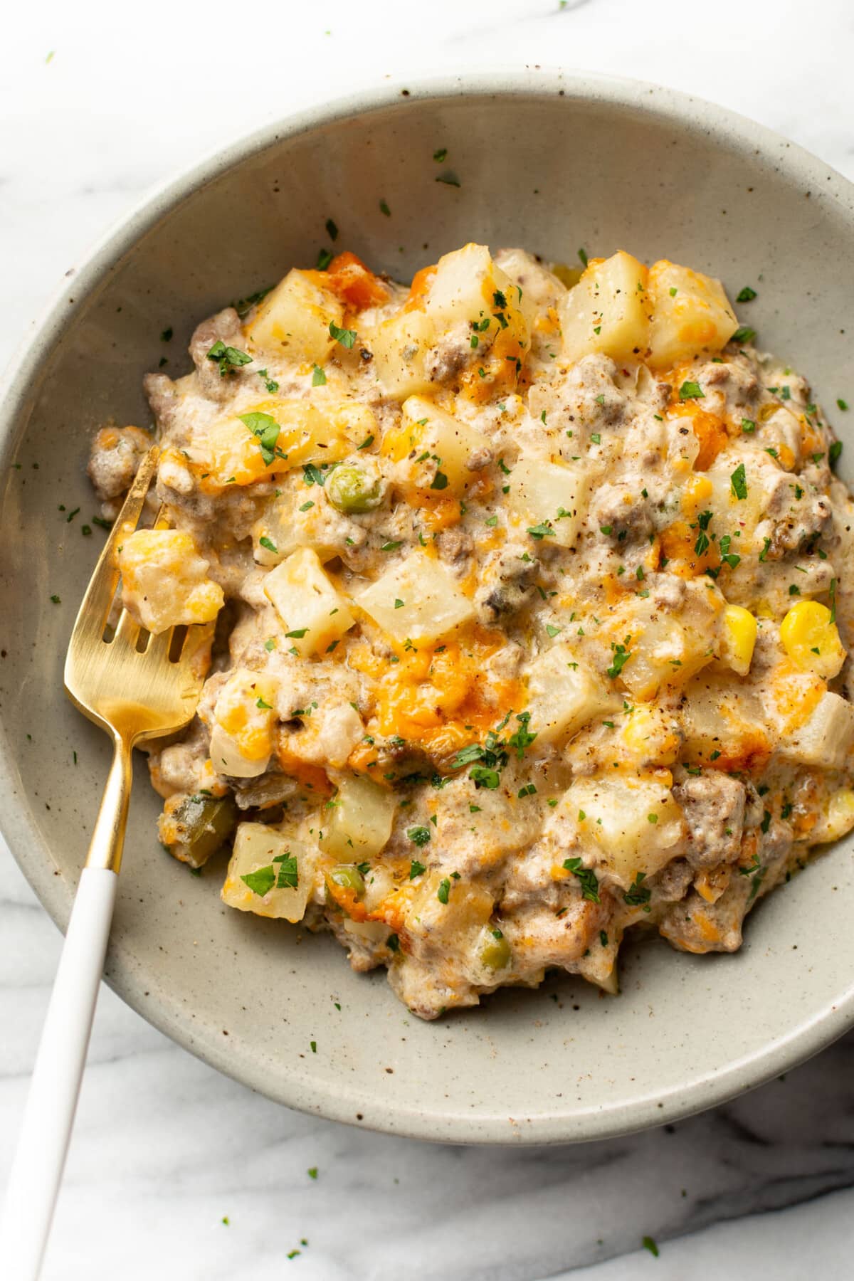 a bowl with a serving of ground beef and potato casserole with a fork
