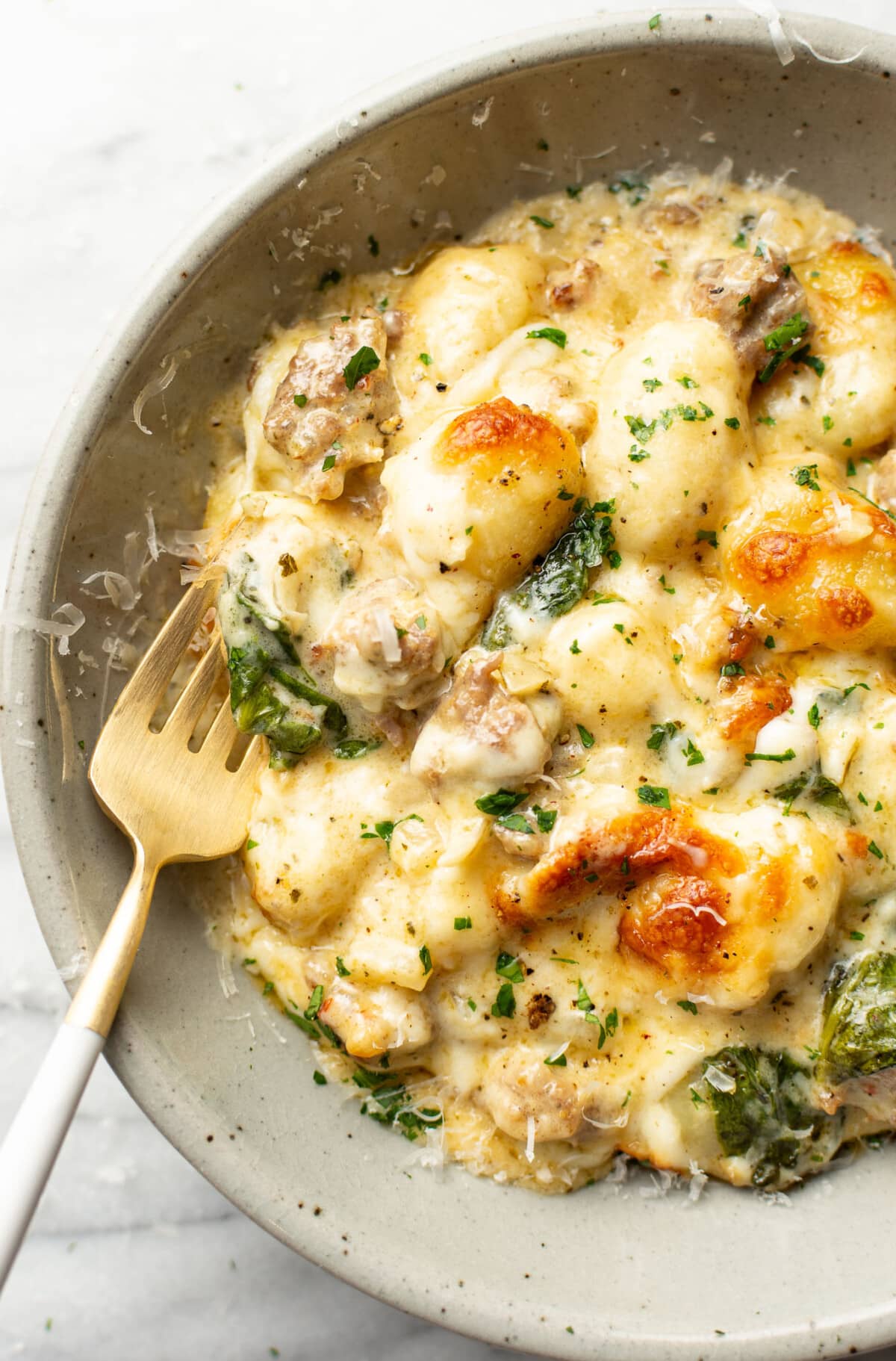 a bowl with a portion of pesto sausage gnocchi bake with a fork