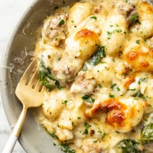 a bowl with a portion of pesto sausage gnocchi bake with a fork