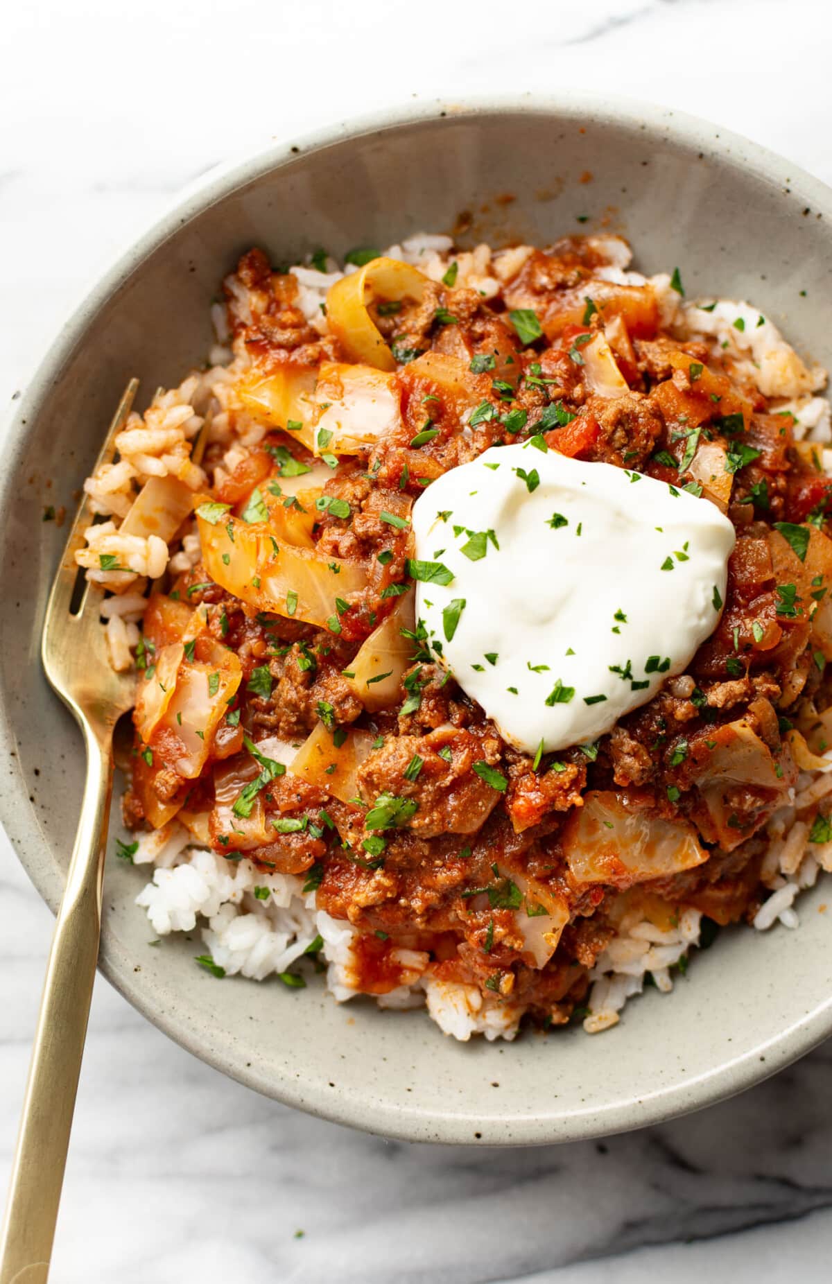 a bowl of unstuffed cabbage rolls over rice with a fork