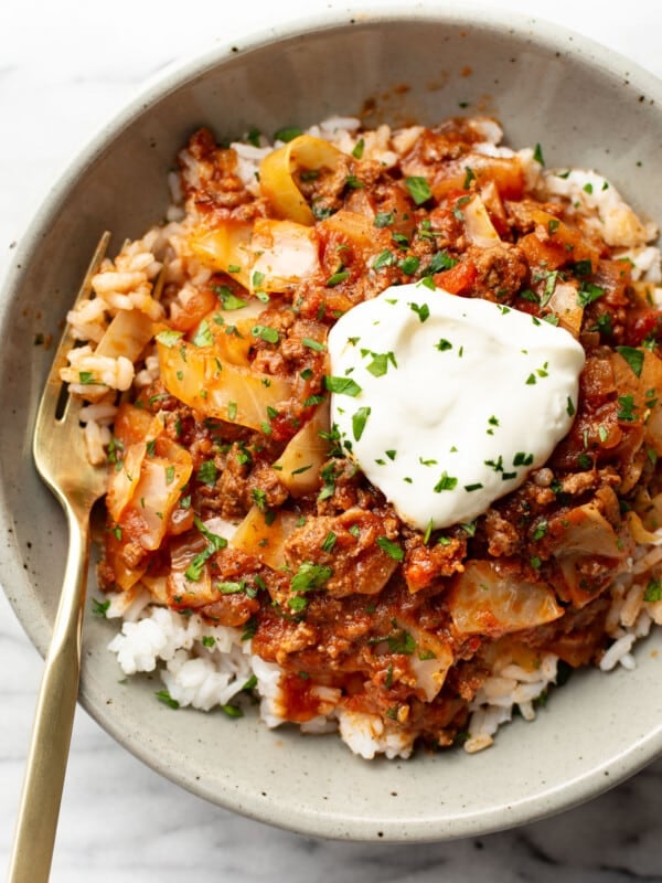 a bowl of unstuffed cabbage rolls over rice with a fork