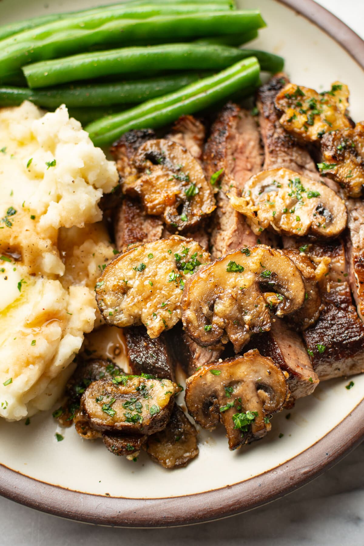 a plate with steak, air fryer mushrooms, mashed potatoes, and green beans