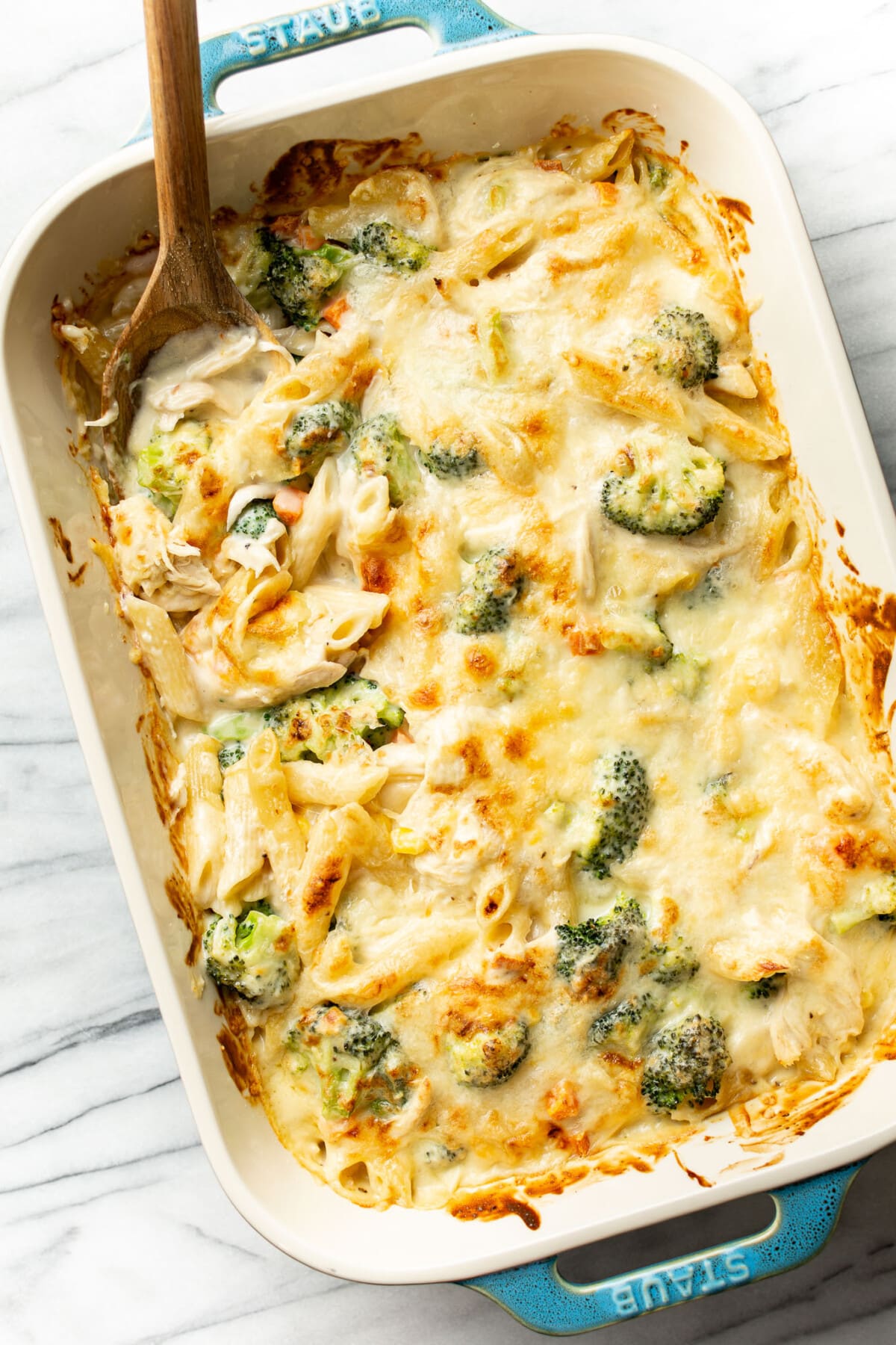 a baking dish with chicken penne casserole and a serving spoon