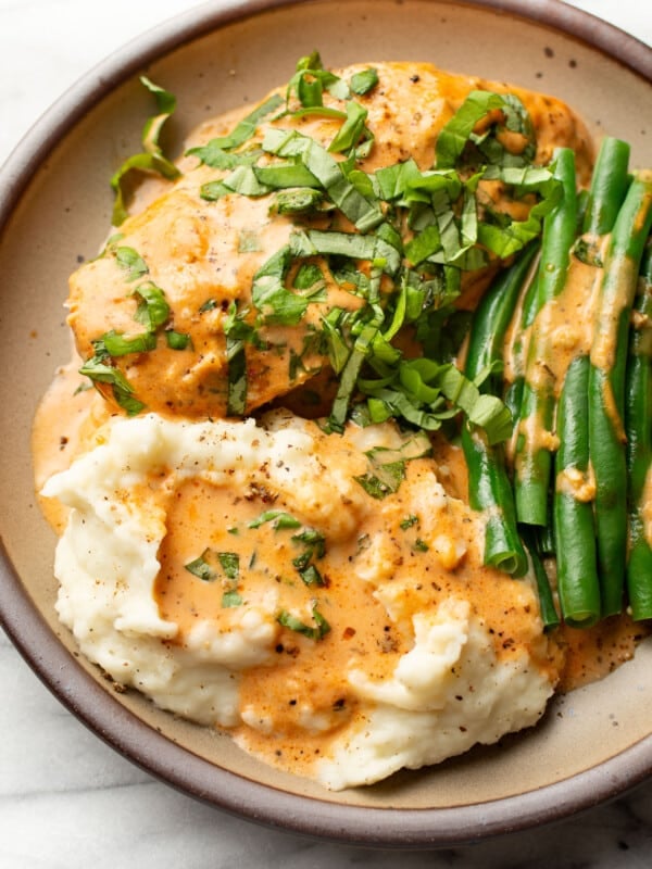 a plate with baked tomato basil chicken, green beans, and mashed potatoes
