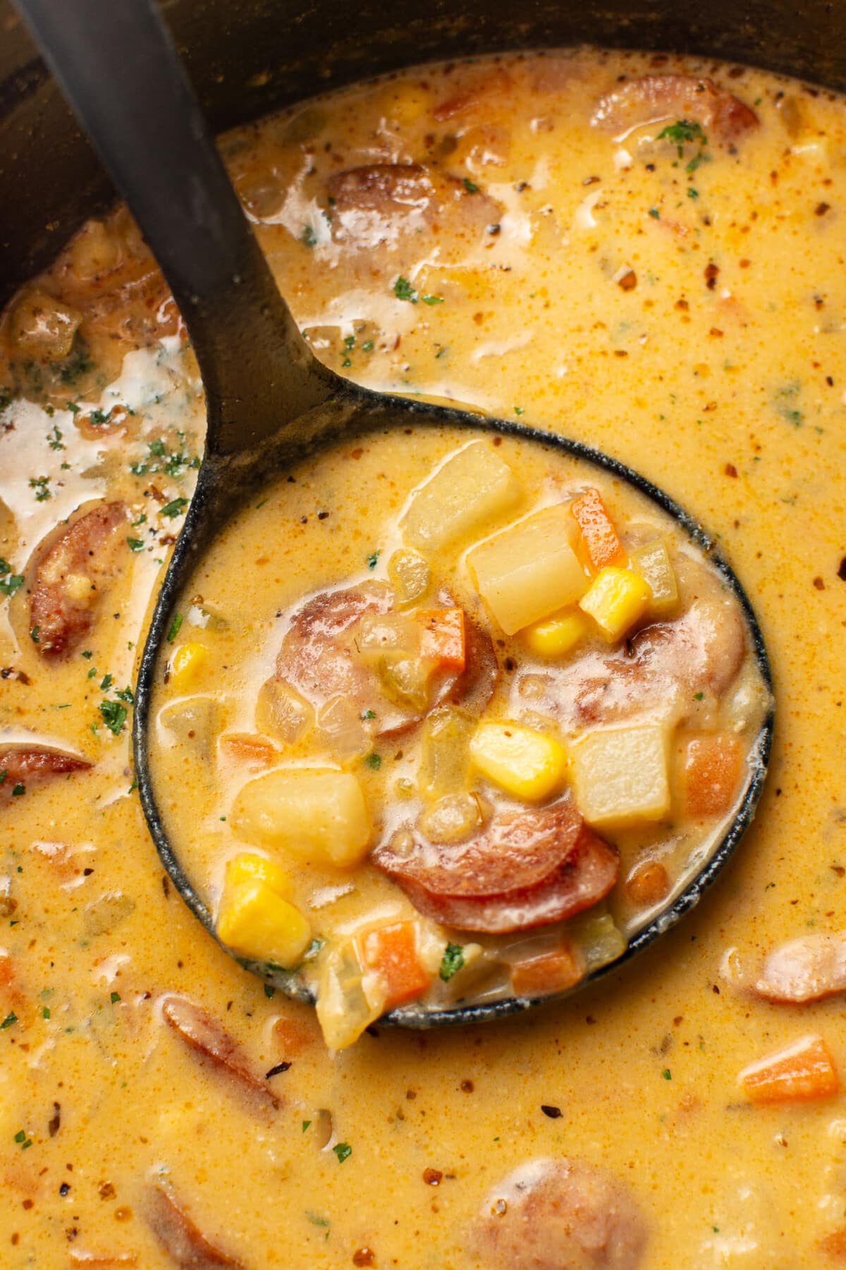 a ladle with creamy kielbasa potato soup