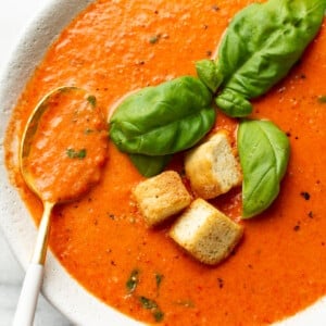 a bowl of roasted red pepper soup with a spoon